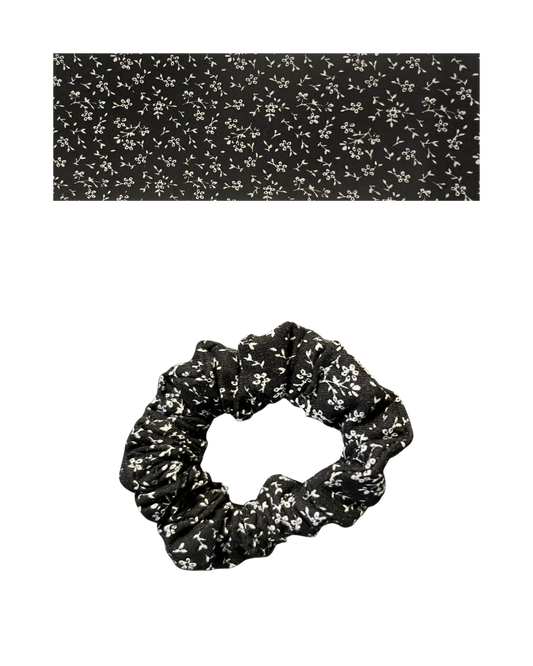 Black scrunchie on a white floral patterned.